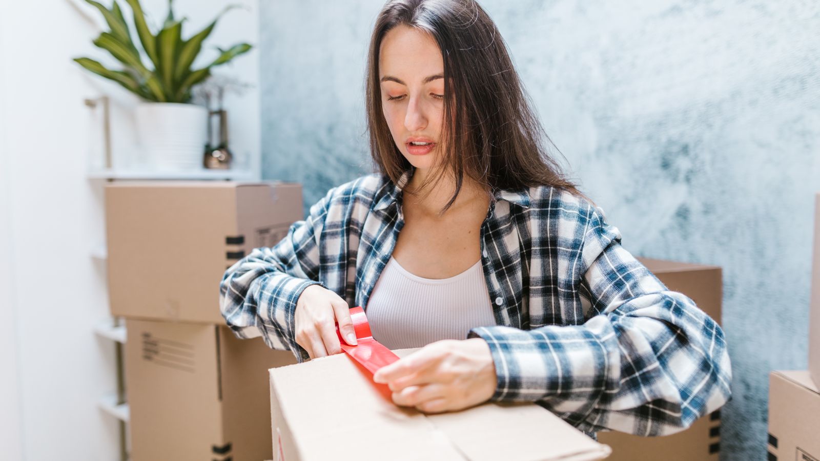 Mujer preparando y sellando cajas para trasladar sus pertenencias