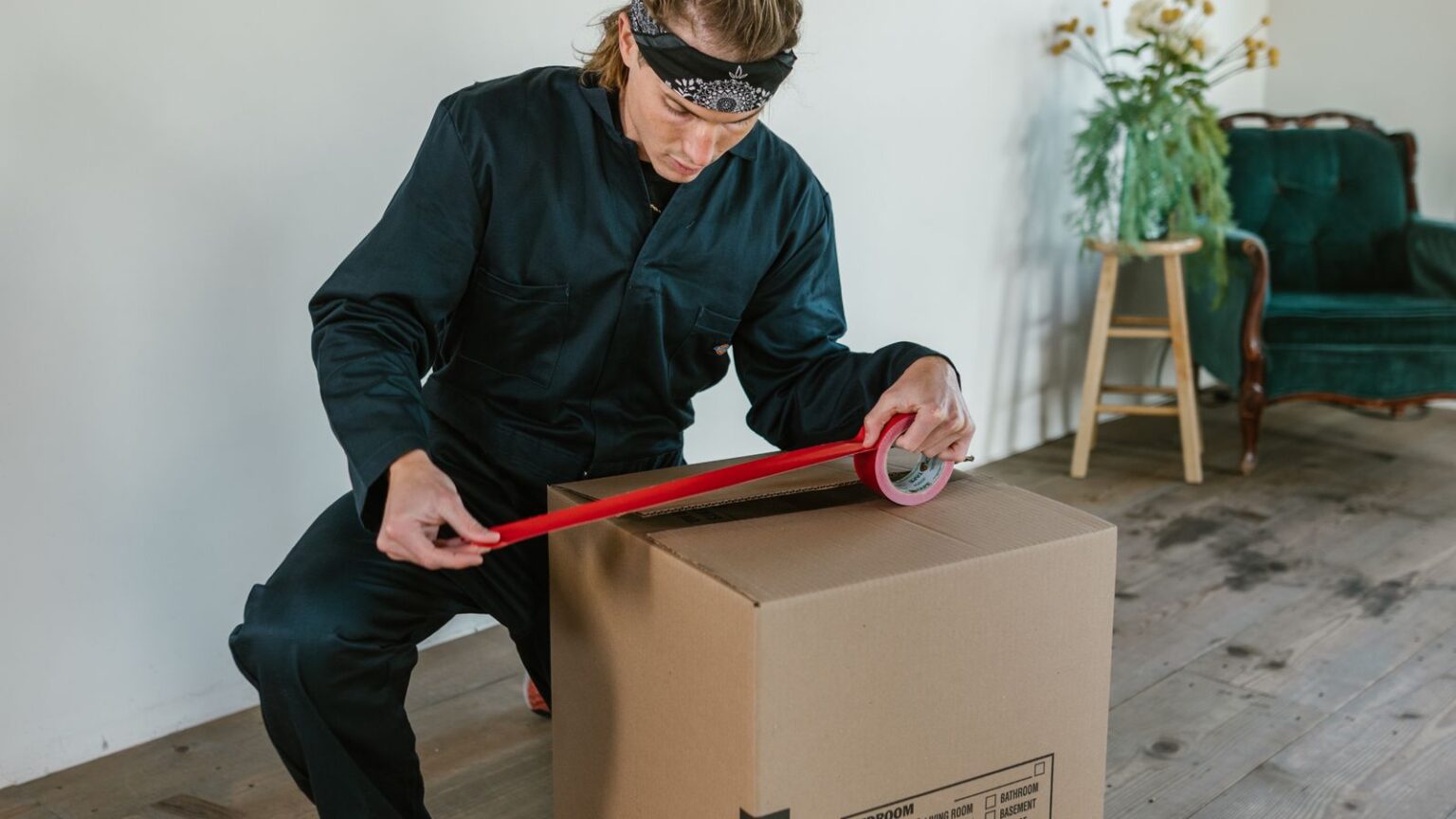 Hombre sellando una caja de mudanza con cinta adhesiva
